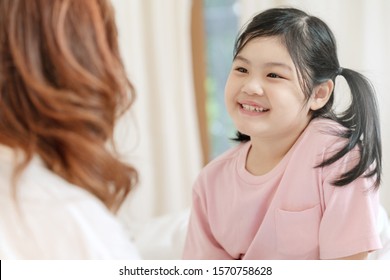 Happy Little Asian Girl Smiling, Looking And Talking With Mother. Cute Child Feeling Confident And Proud Because Praise From Mom. Encourage Confident And Self Esteem Concept.