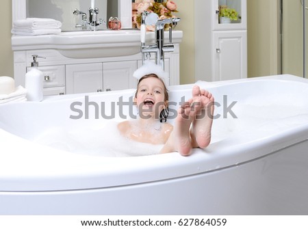 Happy little baby girl face swimming in the bathroom. Portrait of baby bathing in a bath full of foam