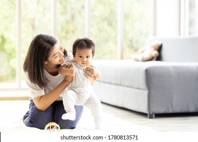 Happy little baby learning to walk with mother help in living room. Baby taking his first steps with mother's help and support with love. - Shutterstock ID 1780813571