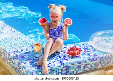 happy little blonde girl laughing by the pool eating fruit and drinking lemonade. family vacation concept
