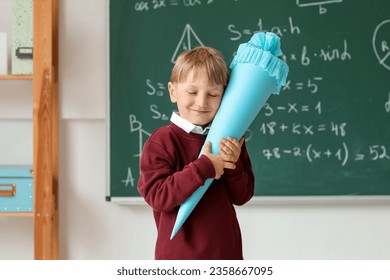 Happy little boy with blue school cone in classroom near blackboard - Powered by Shutterstock