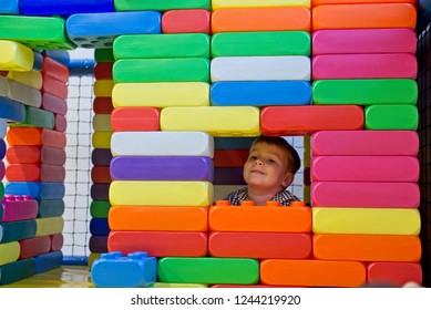 Happy little boy builds house from plastic blocks
