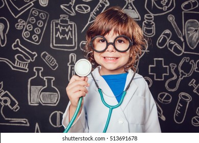 Happy Little Boy In Doctor Costume Holding Sthetoscope On Dark Background With Pattern. The Child Has Glasses