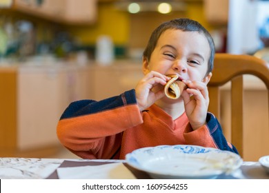 Happy little boy eats pancakes hands. Portrait of small cute little boy child caucasian sitting by the table at home eating pancake