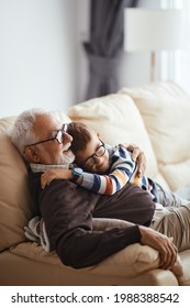 Happy little boy embracing his grandfather while spending time together at home.  - Shutterstock ID 1988388542