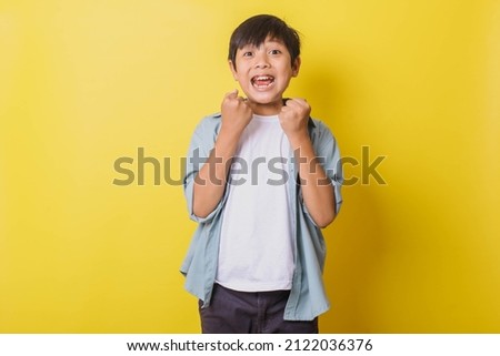 Happy little boy with gesture celebrating isolated on yellow background