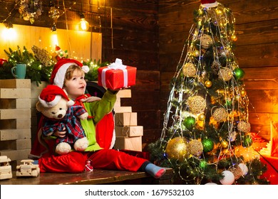 Happy Little Boy With His Teddy Bear And Christmas Gift Is Trying To Guess What Is Inside The Gift. Winter, Holiday, Family Time