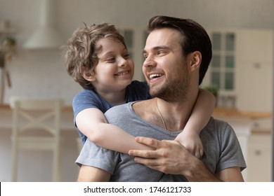 Happy Little Boy Hug Young Father Relax Play Together At Home On Leisure Weekend, Smiling Small Preschooler Son Embrace Dad Show Love And Care, Family Bonding, Children Gratitude Concept