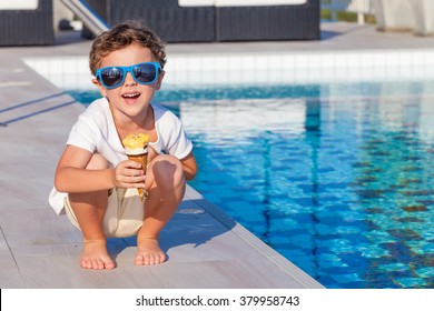 Happy Little Boy With Ice Cream Sitting Near A Swimming Pool At The Day Time.