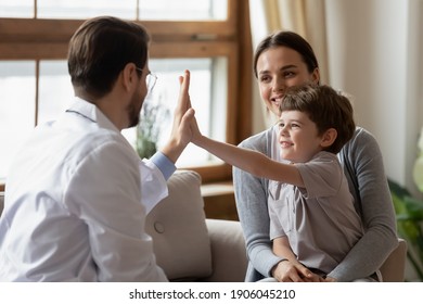 Happy Little Boy Patient With Mom Give High Five To Caring Male Pediatrician After Consultation In Hospital. Caring Man Doctor Cheer Greet With Small Child At Checkup In Clinic. Healthcare Concept.