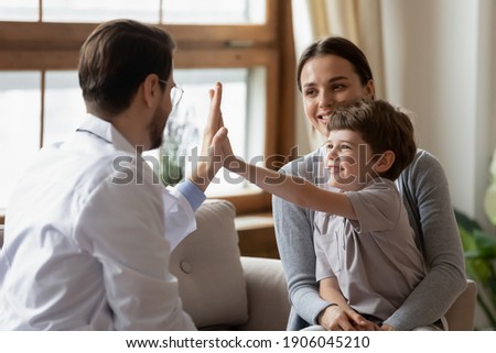 Happy little boy patient with mom give high five to caring male pediatrician after consultation in hospital. Caring man doctor cheer greet with small child at checkup in clinic. Healthcare concept. ストックフォト © 