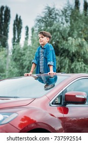 Happy Little Boy Peering Out Of Sun Roof Of Car