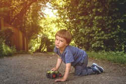 Happy Little Boy Plays With Toy Car Outdoors. Child Crawling On Road In Park. Kid With Tractor In Nature. Tree Years Old.