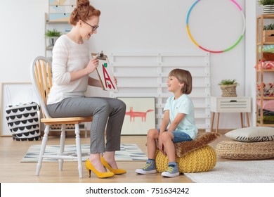 Happy Little Boy With Pronunciation And Language Difficulties During Speech Therapy Session With Young Female Doctor