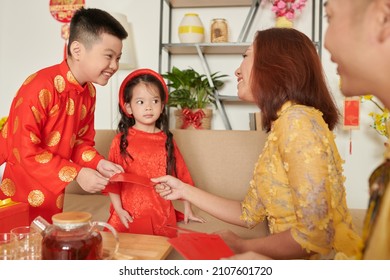 Happy Little Boy Receiving Red Envelope Symbolizing Good Luck From Parents For Spring Festival