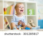 Happy little boy. Smiling child toddler plays animal toys at home or kindergarten.