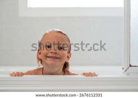 Happy little boy smiling while leaning on bathtub edge after bat