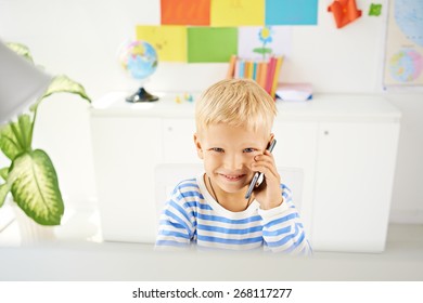 Happy Little Boy Talking On Smartphone In The Class