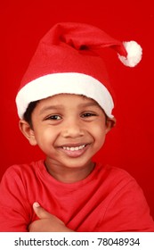 A happy little boy wearing a santa hat in a red background