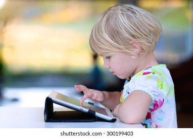 Happy Little Child, Adorable Blonde Toddler Girl Enjoying Modern Generation Technologies Playing Indoors Using Tablet Pc With Touchscreen