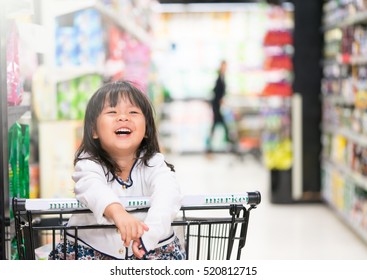 Happy Little Child Asian Toddler Girl, Sitting In The Trolley With Family Shopping In Hypermarket.supermarket Grocery Store.Asian Baby Toddler Child Girl Shopping With Mother.Smile Oral Care.product.