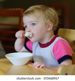 Happy Little Child, Blonde Toddler Girl Eating Tasty Ice Cream From Bowl In Cafe