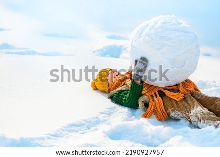 Happy little child boy lying in snow with big snow globe. Happy winter holidays concept. Place for text of positive news, advertising.