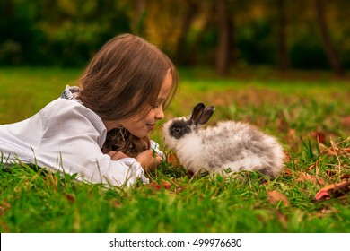 Happy Little Child Girl With Cute Rabbit. Portrait Of Kid With Pet. Outdoors.