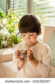 Happy Little Child Holding In Hands Glass Jar Full Of Coins. Kid Counting Money Saving From Change Learning Financial Literacy.