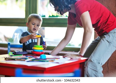 Happy Little Child Play Game And Have Fun, Education Lessons In Colorful Kinder Garden Playground Indoors