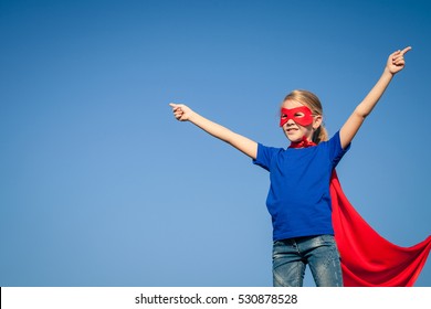 Happy little child playing superhero. Kid having fun outdoors. Concept of girl power.