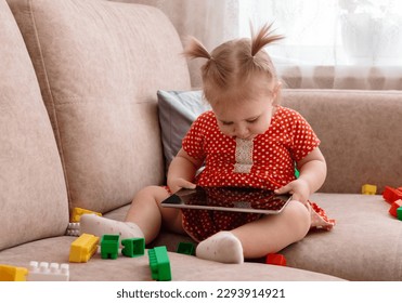 Happy little child sitting on sofa and using tablet.  - Powered by Shutterstock