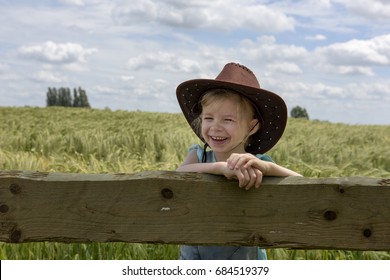 Happy little cowgirl looking over a fence