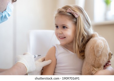 Happy Little Cute Blonde Girl Holding A Toy And Getting A Flu Shot Not Afraid Of The Syringe Needle. Doctor Injecting Brave Child With Covid-19 Vaccine At Clinic
Immunization For Children Concept. 