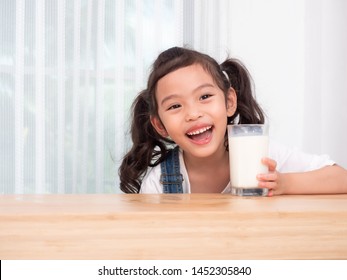 Happy Little Cute Girl 6 Years Old Drinking Milk From Glass. Kid Smiling And Laughing After Drinking And The Milk Splatter.