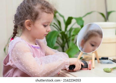 Happy little cute girl playing with her mother's cosmetic, selfcare, beauty procedure Treatment, makeup, visage, powdering face in front of mirror at home.