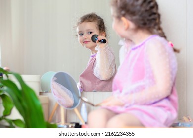 Happy little cute girl playing with her mother's cosmetic, selfcare, beauty procedure Treatment, makeup, visage, powdering face in front of mirror at home. 