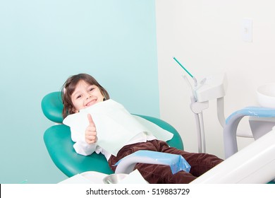 Happy little cute girl smiling and showing OK sign at dental clinic