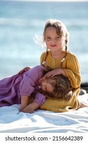 Happy Little Cute Girls Enjoying Sunny Day At The Beach, Hugging And Smiling To The Camera. Family Summer Vacation. Sister's Love. A Lot Of Copy Space.
