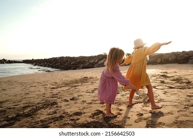 Happy Little Cute Girls Enjoying Sunny Day At The Beach, Playing And Running On The Sand. Family Summer Vacation. Sister's Love. A Lot Of Copy Space.
