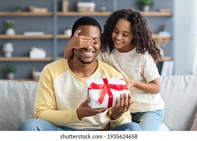 Happy little daughter giving present to her dad