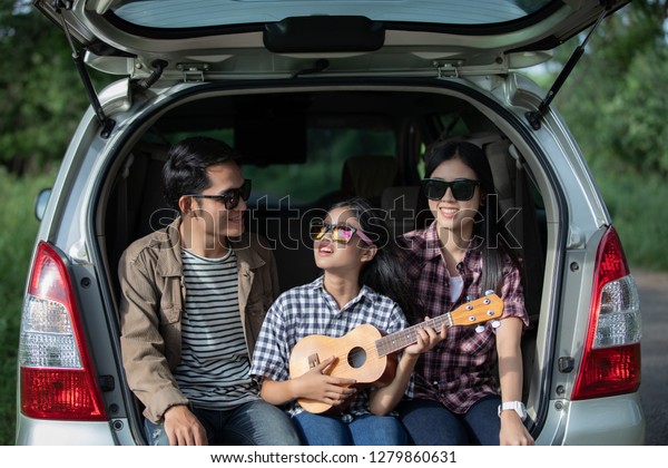 Happy little girl \
with asian family sitting in the car for enjoying road trip and\
summer vacation in camper\
van