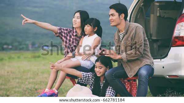 Happy little girl \
with asian family sitting in the car for enjoying road trip and\
summer vacation in camper\
van