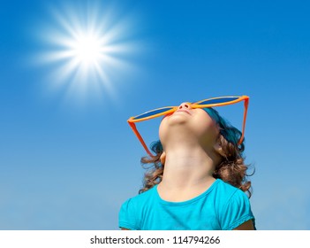 Happy Little Girl With Big Sunglasses Looking At The Sky With Sun In Summer