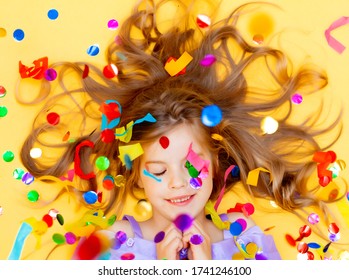 Happy little girl in a blue dress celebrates a party with confetti top view. Birthday child, positive emotions.