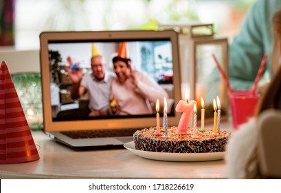 Happy little girl celebrating birthday at home with parents and grand parents on video call. Laptop with senior couple online, cake with candles on table. - Powered by Shutterstock