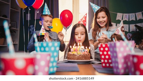 Happy little girl celebrating birthday with friends at home, blowing candles at cake , making wish while sitting at table in living room and children applauding her and laughing. - Powered by Shutterstock