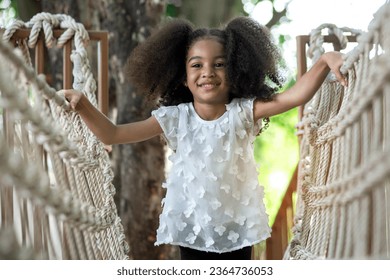 Happy little girl climbing on the Rope bridge in adventure park, having fun at playground   - Shutterstock ID 2364736053
