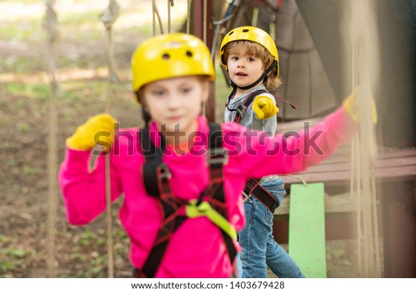Happy little girl climbing in the trees.\
Happy Little girl climbing on a rope playground outdoor. Toddler\
kindergarten. Balance beam and rope\
bridges