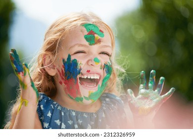 Happy  little girl covered in paint   outdoors and lens flare  Happiness creative  playing art fun   cheerful excited young child and painting over her face outside in the summer